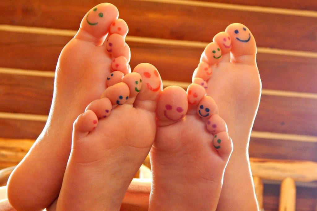 Feet with smiley faces drawn on toes in a cozy room