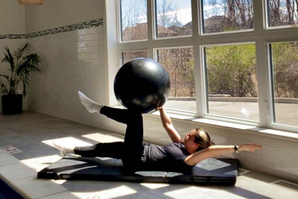 Woman exercising with yoga ball in sunlit studio
