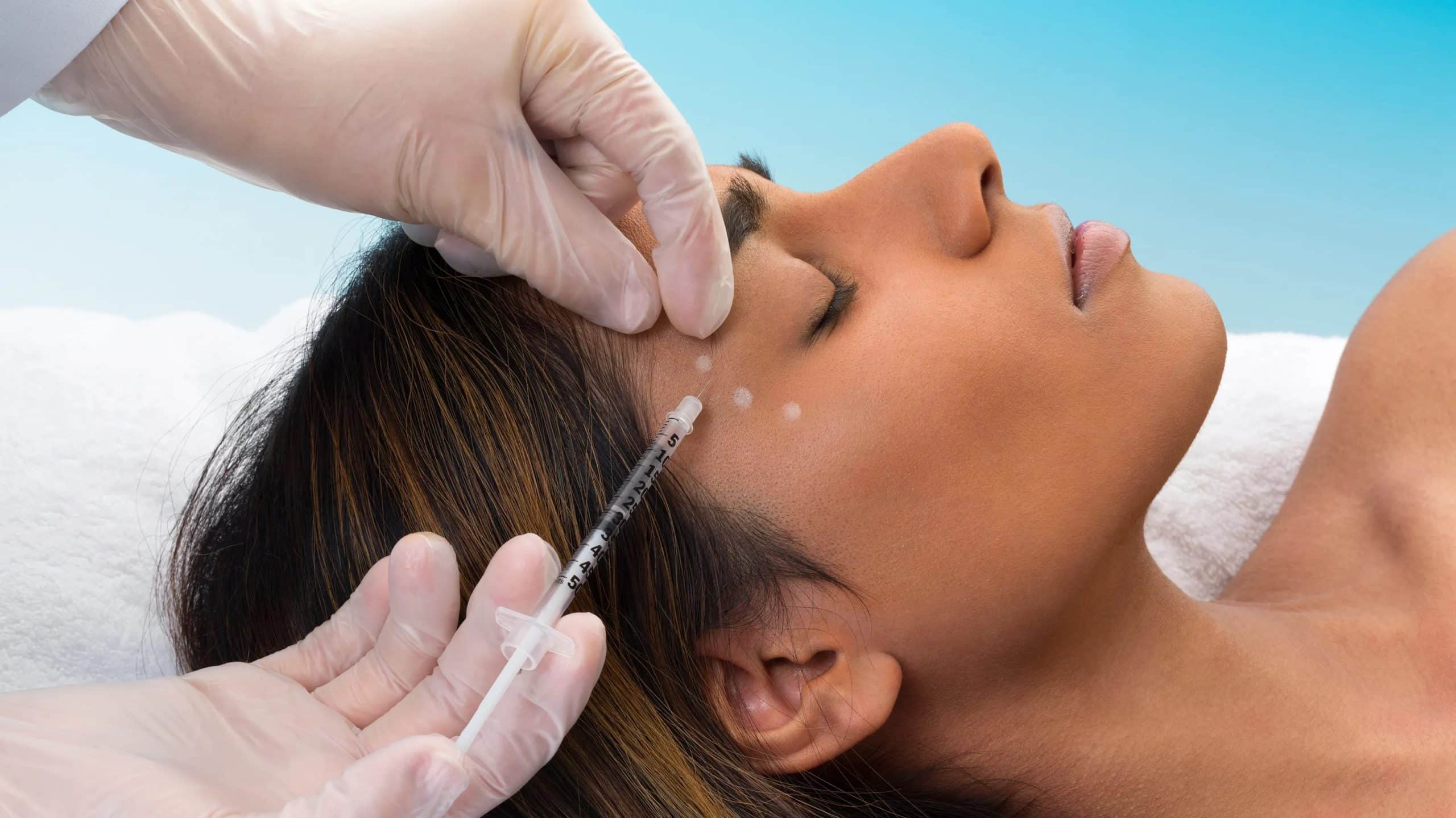 Cosmetic injection procedure on woman's forehead