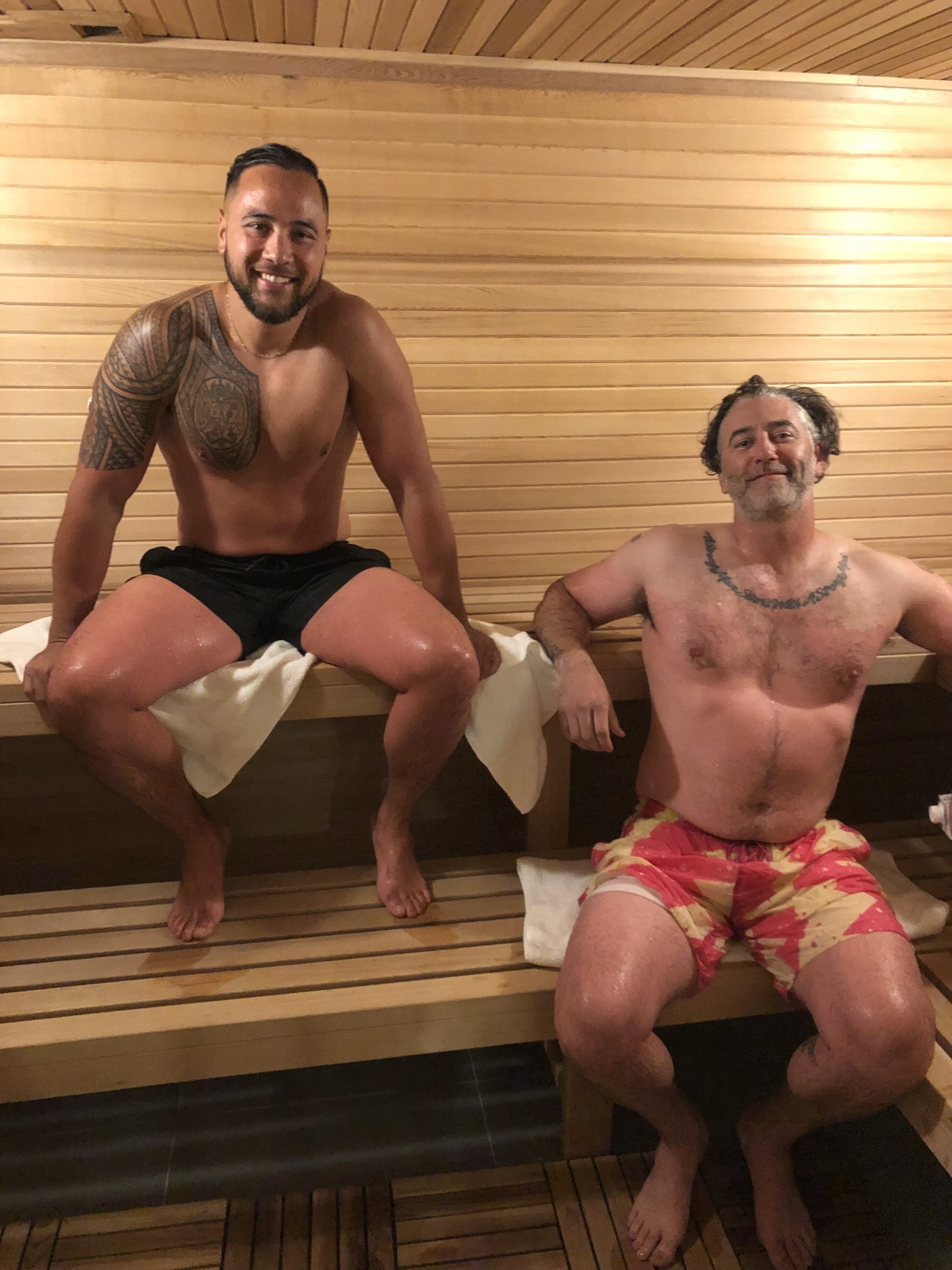 Two men sitting in a wooden sauna enjoying the warmth